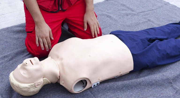 Man practising CPR using torso dummy.